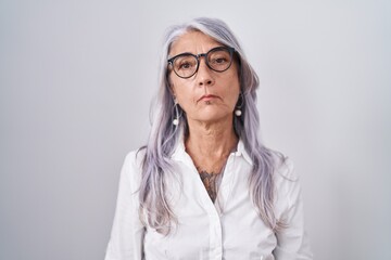 Middle age woman with tattoos wearing glasses standing over white background relaxed with serious expression on face. simple and natural looking at the camera.