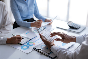 Business people working together planning investment marketing and using calculator at meeting.