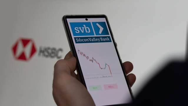March 26th 2023. An investor analyzing the svb Silicon Valley Bank's stocks on a screen, the logo of HSBC is behind on the background. 