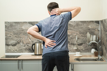 Back pain, man with backache at home on pink background