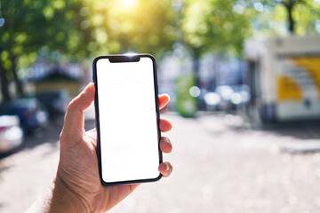 Man holding smartphone showing white blank screen at street