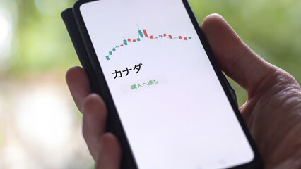 Investor analyzing an ETF. Funds stocks exchange ETFs Japanese text: Canada, buy. カナダ 証券取引所 投資 shares