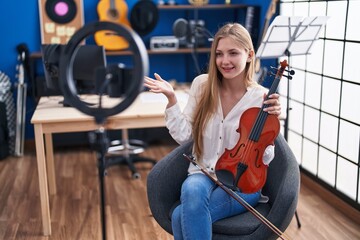 Fototapeta na wymiar Young caucasian woman musician having online violin lesson at music studio