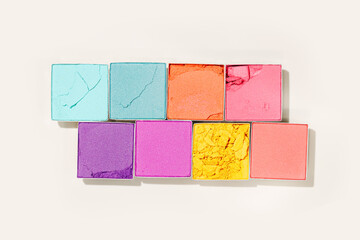 Cosmetic beauty product multicolor eyeshadows for makeup on beige colored background, color pallete swatches powder eyes, top view, flat lay pattern, cosmetic beauty product, shiny eye shadow