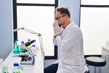 Naklejka na ściany i meble Young caucasian man scientist using napkin at laboratory