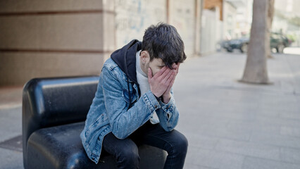 Young hispanic man stressed sitting on a bench at street