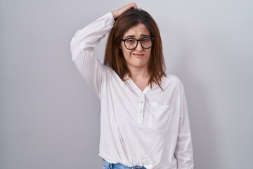 Brunette woman standing over white isolated background confuse and wondering about question. uncertain with doubt, thinking with hand on head. pensive concept.