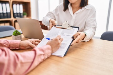 Man and woman business workers signing contract at office