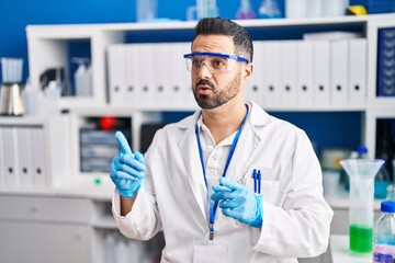 Young hispanic man scientist speaking at laboratory