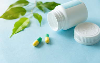 Capsules green in an open jar with leaf some tablets are on the table