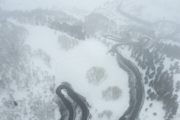 Fototapeta premium A snake shaped pass road in winter photographed from above. Birds eye view