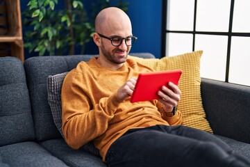 Young man using touchpad sitting on sofa at home