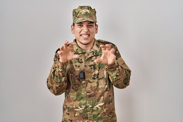 Young arab man wearing camouflage army uniform smiling funny doing claw gesture as cat, aggressive...