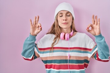 Young blonde woman standing over pink background relax and smiling with eyes closed doing meditation gesture with fingers. yoga concept.