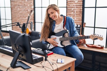 Fototapeta na wymiar Young blonde woman musician playing electrical guitar at music studio
