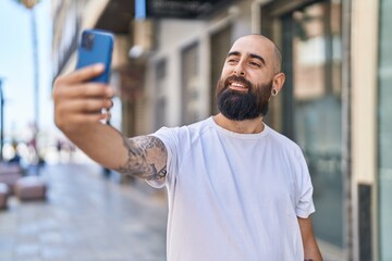 Young bald man smiling confident making selfie by the smartphone at street