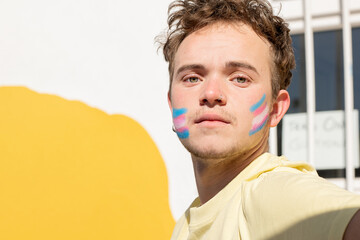 transgender man with transgender flag painted on his face