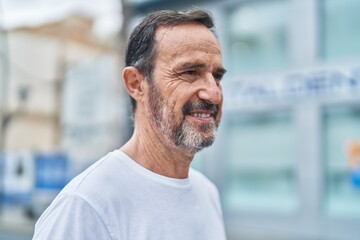 Naklejka premium Middle age man smiling confident looking to the side at street