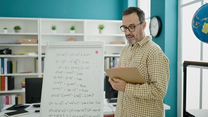 Fototapeta na wymiar Middle age man teacher teaching lesson reading document at classroom