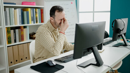 Middle age man teacher working stressed at classroom
