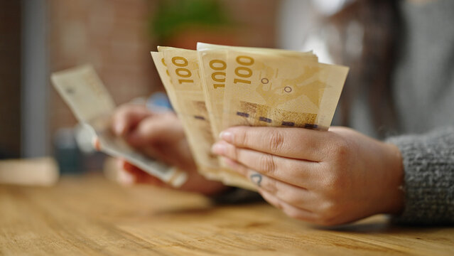 Hands of woman counting hundred denmark krone banknotes at room