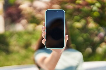 Adorable girl showing screen smartphone at park