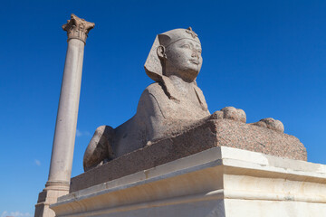 Ancient stone sphinx with Pompeys Pillar on a background. Alexandria