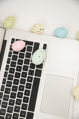 Computer with blank empty screen on white background of easter eggs. Space for text. Happy Easter! 