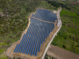 Flying over a solar farm with photovoltaic panels converting solar power to electricity for green...