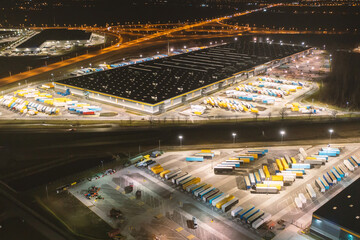 Fototapeta na wymiar Aerial view of a warehouse of goods at night. Aerial view of industrial area, logistics warehouses and many trucks at night