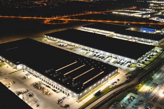 Aerial view of a warehouse of goods at night. Aerial view of industrial area, logistics warehouses and many trucks at night