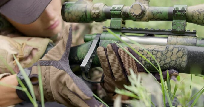 female soldier lying , sitting on grass, camouflage getting ready for military operation, loading weapons in countryside