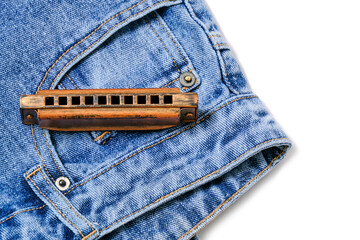 Harmonica, musical instrument, lies on denim pants.