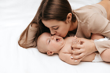 The older sister is kissing newborn sister on a white background.