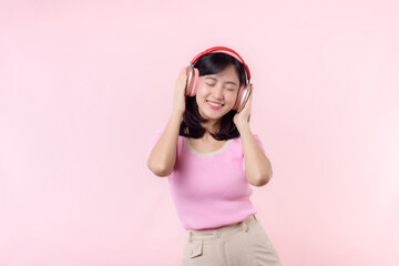 Smile pretty model person listen music song and enjoy dance with wireless headphone online audio radio sound. Positive fun exited joyful youth female woman sing on pink isolated background studio