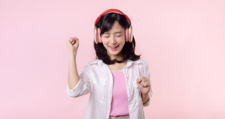 Smile pretty asian model person listen music song and enjoy dance with wireless headphone online audio radio sound. Positive fun exited joyful youth female woman on pink isolated background studio