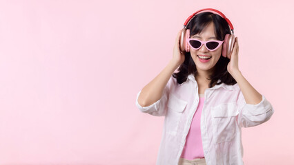 happy young asian woman model with stylish trendy sun glasses enjoy listening music by headphone...