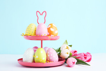 Stand with colorful easter eggs and bouquet tulips on blue background