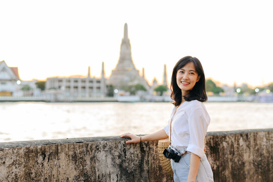 Portrait young beautiful asian woman smiling while travel at Wat Arun sunset view point, Bangkok, Thailand.
