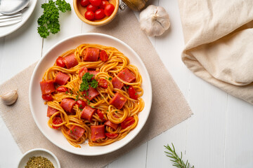 Hot dog or sausage stuffed with spaghetti in tomato sauce in white plate.Top view