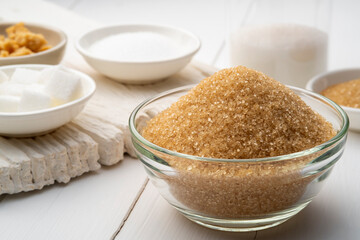 Yellow sanding cane sugar in glass bowl,Various granulated sugar on white table
