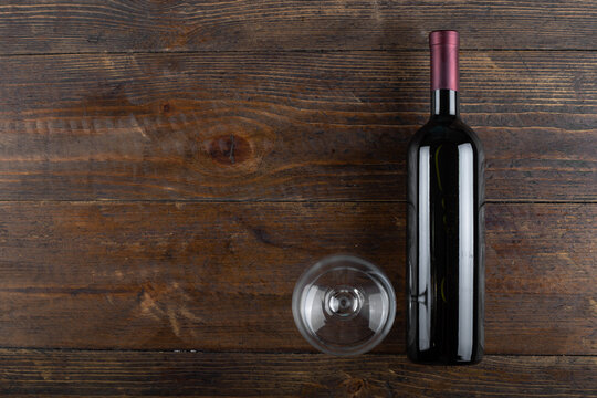 Glass and bottle of red wine on a wooden background. Top view