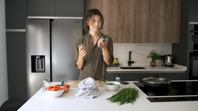 Smiling asian young man checking recipe spices at kitchen.