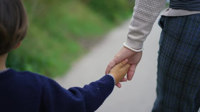 Closeup child and mother holding hands walking outside. Hand of parent and kid held together going for a walk together