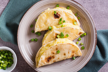 Tortillas stuffed with mashed potatoes and onions on a plate close-up