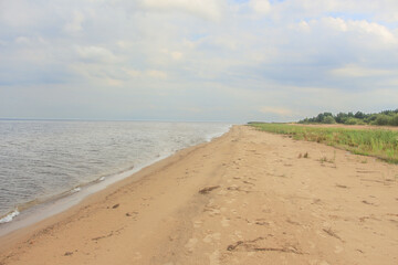 Fototapeta na wymiar Landscape: Sandy seashore with rolling waves under a cloudy sky