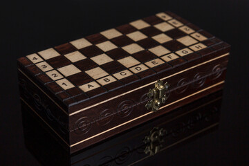 Closed chess box on a black background with reflection. Intellectual game and sports. Close-up.