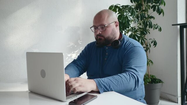 Plus size men in glasses working at laptop in cafe or coworking
