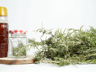 Close up, glass jar with rosemary, next to a container with honey.