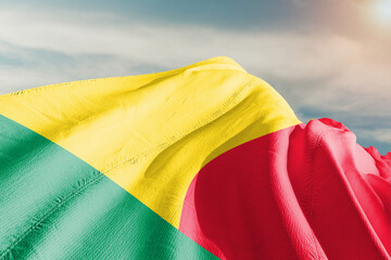 Benin national flag cloth fabric waving on beautiful grey background.